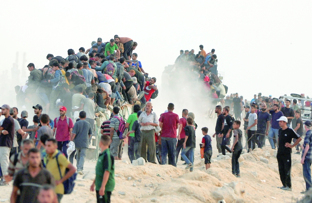 
Palestinians climb onto trucks carrying aid supplies that entered Gaza in Beit Lahia on Tuesday. — Reuters 