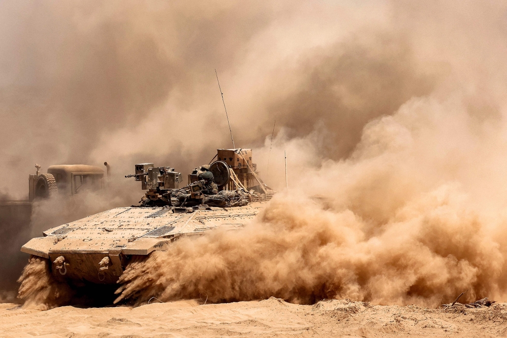 An Israeli army infantry fighting vehicle (IFV) leaves a cloud of dust as it moves at a position along the border with the Gaza Strip and southern Israel on July 29, 2025. 