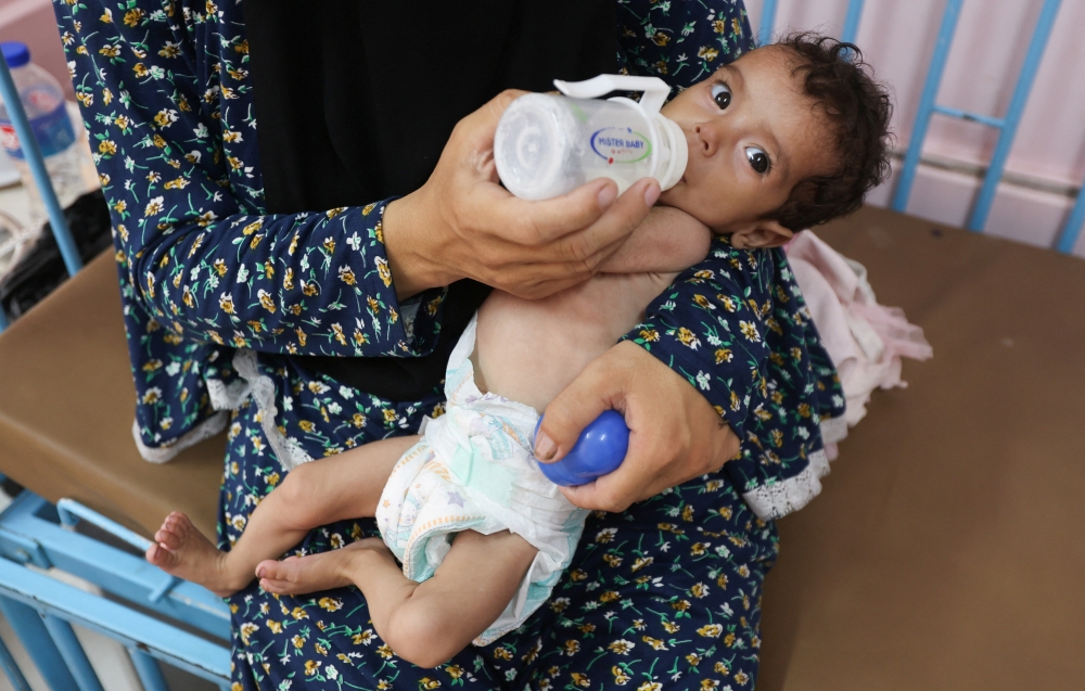Palestinian woman Najla Abu Aya feeds her five-month-old daughter, Rama, who is malnourished, according to medics, at Nasser Hospital in Khan Younis, southern Gaza Strip, July 24, 2025. 