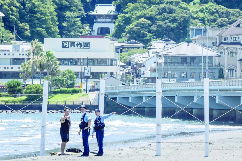 
Police officers ask a man to evacuate an empty beach due to a tsunami warning in Fujisawa city. — AFP 