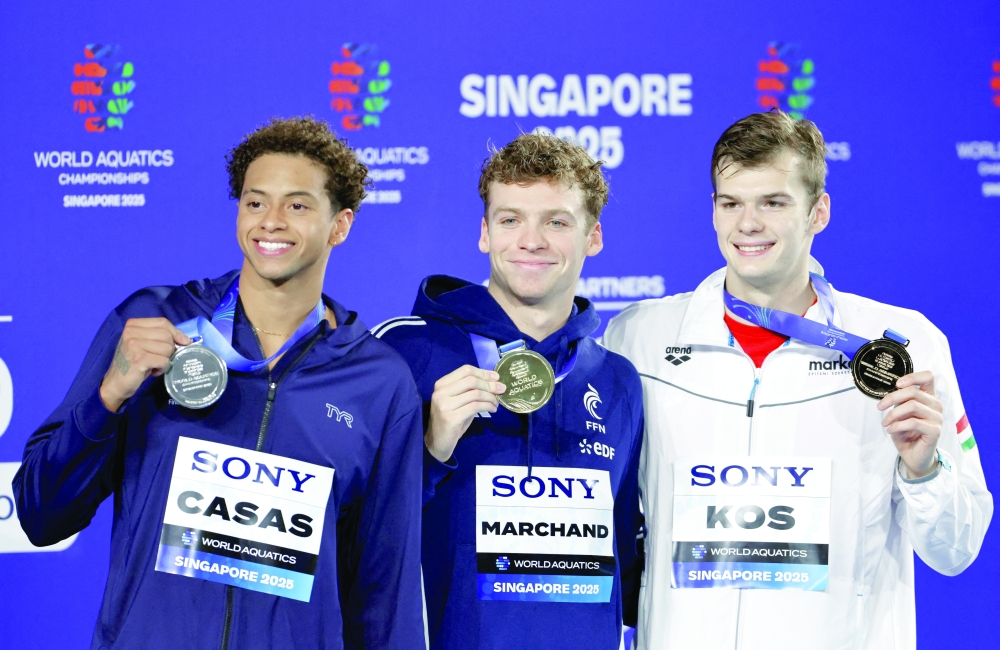 Gold medallist France's Leon Marchand celebrates on the podium alongside silver medallist Shaine Casas of the US and bronze medallist Hungary's Hubert Kos. — Reuters