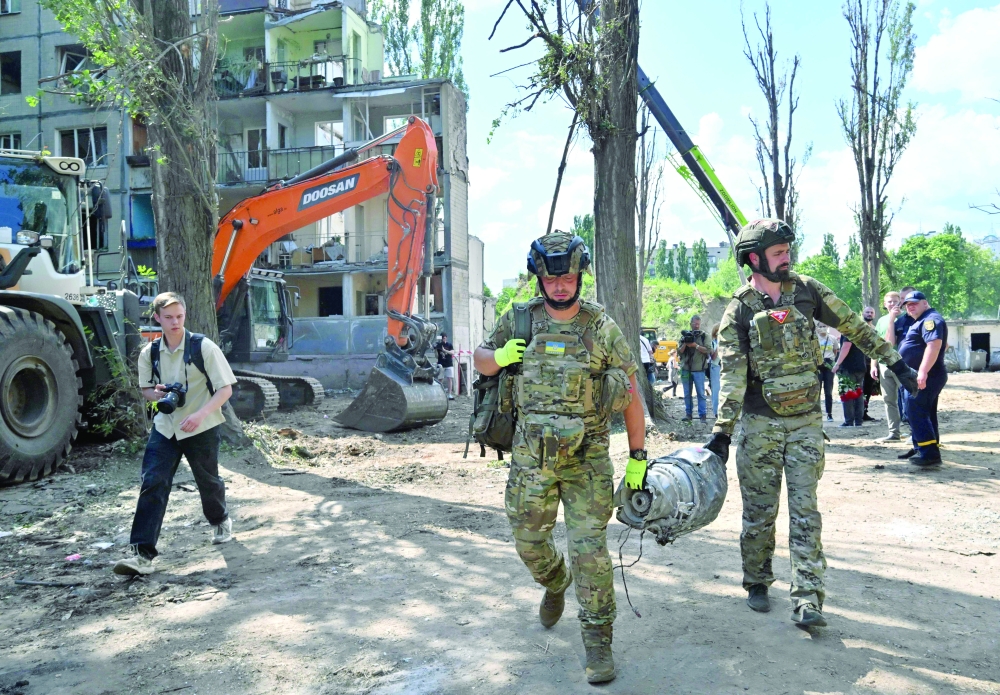 Police explosives experts carry a fragment of Russian cruise missile outside a residential building in Kyiv partially destroyed following a Russian missile strike. — AFP