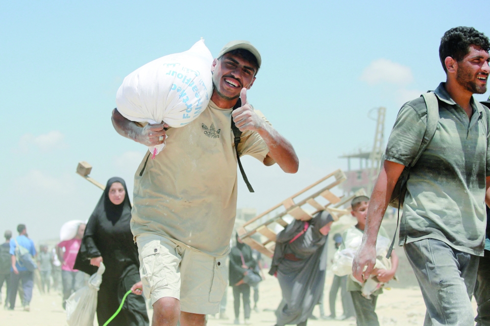 A Palestinian man carries a bag of flour obtained from aid trucks which entered Gaza through the Zikim crossing point, in Jabalia in the northern Gaza Strip. — AFP
