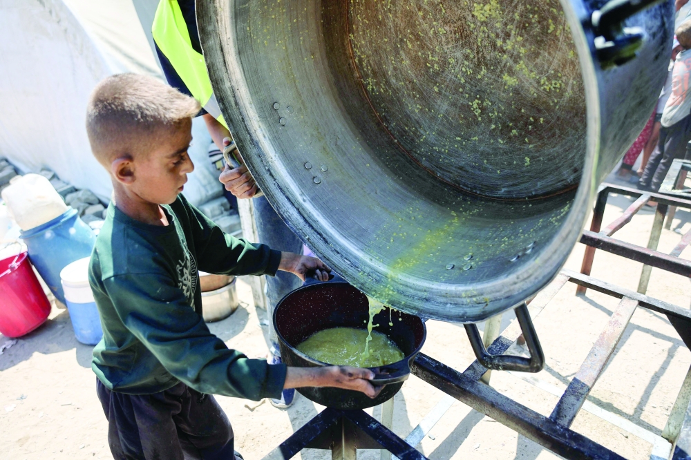 A Palestinian boy receives the last drops of lentil soup at a food distribution point in Gaza City on Friday. — AFP