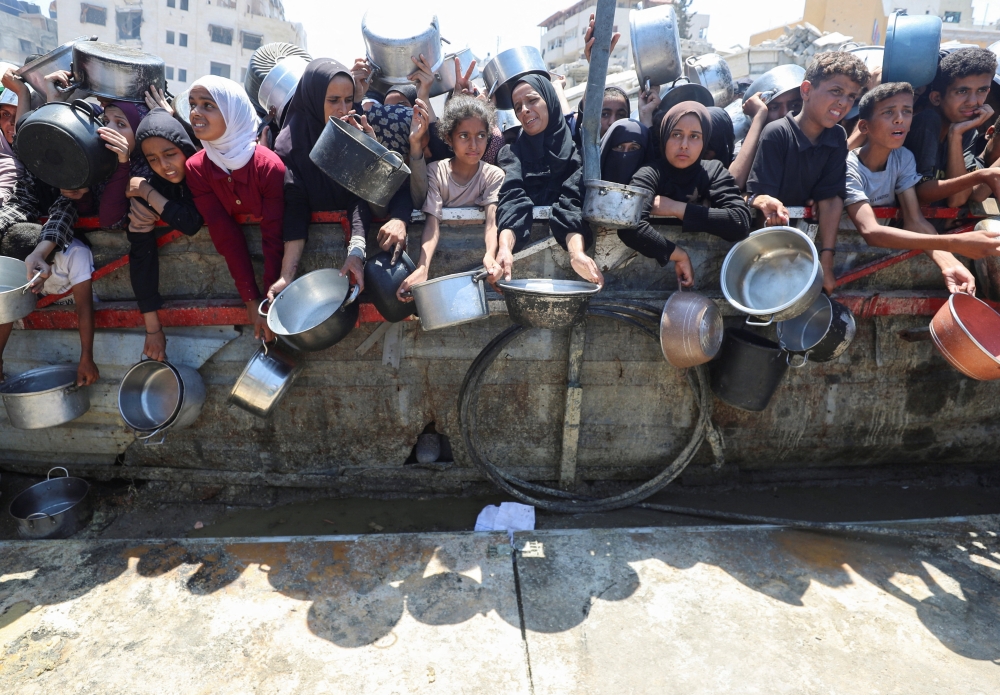 Palestinians wait to receive food from a charity kitchen, amid a hunger crisis, in Gaza City. — Reuters