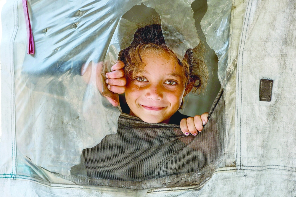 
A Palestinian child poses for a picture from inside a shelter in the Daraj neighbourhood in Gaza City on Sunday. — AFP 