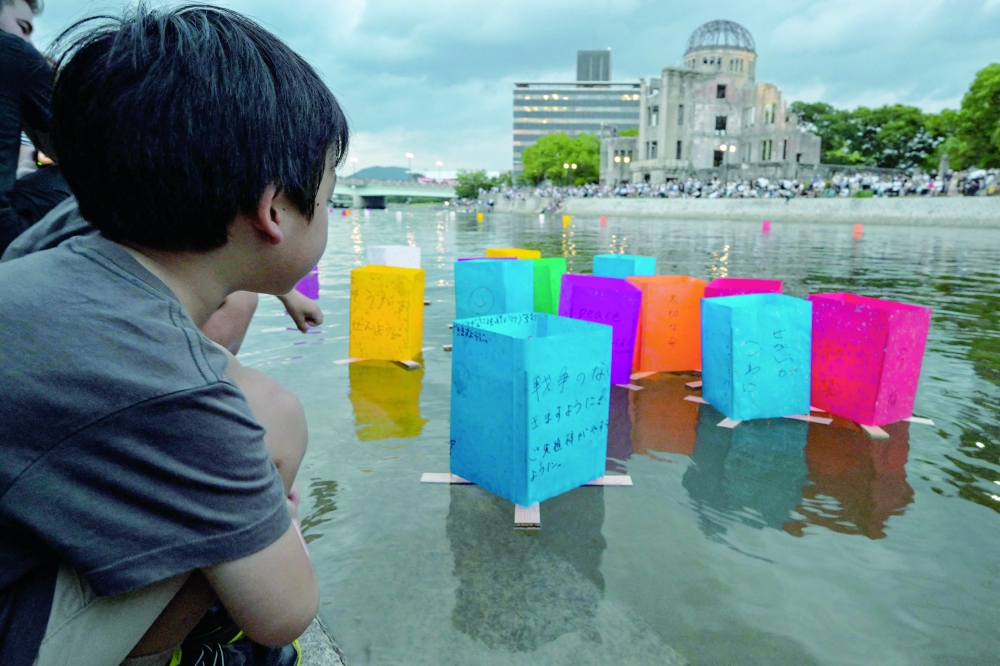 
A young boy watches as his paper lantern floats out on the Motoyasu River past the Atomic Bomb Dome to mark the 80th anniversary of the world’s first atomic bomb attack, in Hiroshima on Wednesday. — AFP 