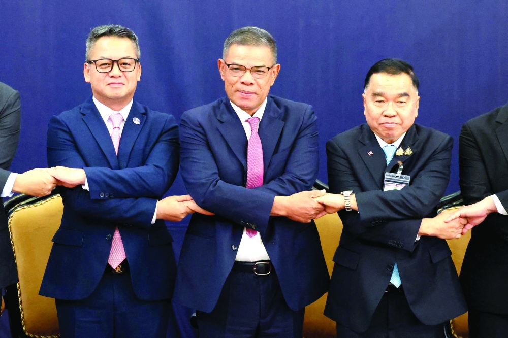
Thai Deputy Defence Minister Nattaphon Narkphanit (L), Malaysian Home Minister Saifuddin Nasution Ismail (C) and Cambodian Defence Minister General Tea Seiha join hands for a group photo ahead of the meeting to discuss border dispute between Thailand and Cambodia in Kuala Lumpur. — AFP 