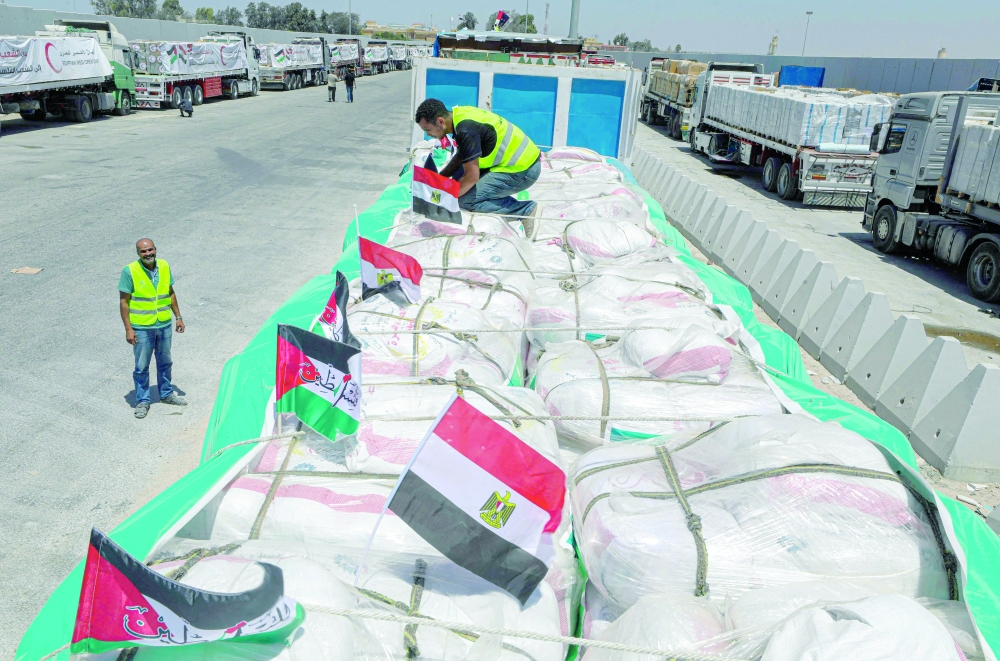 Volunteers arrange parcels as trucks loaded with humanitarian aid await permission on the Egyptian side of the Rafah crossing with the Gaza Strip, to enter the besieged Palestinians territory. - AFP
