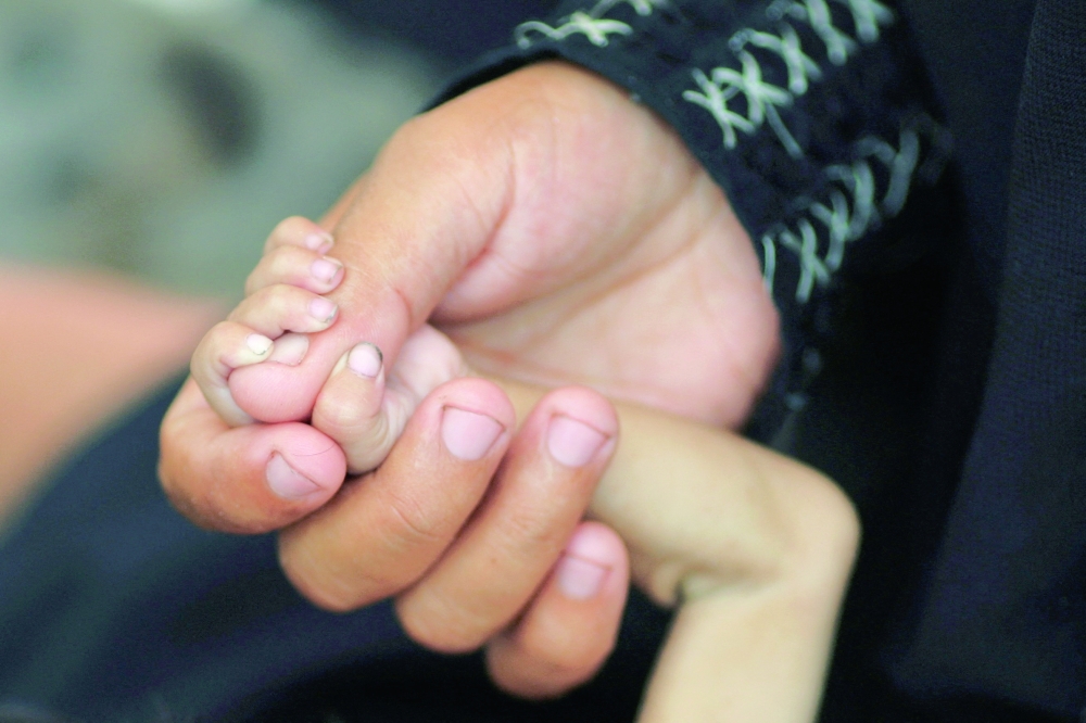 Palestinian mother Amira Muteir holds the hand of her five-month-old baby Ammar, whom she says is wasting away from malnutrition, in Gaza City. — Reuters