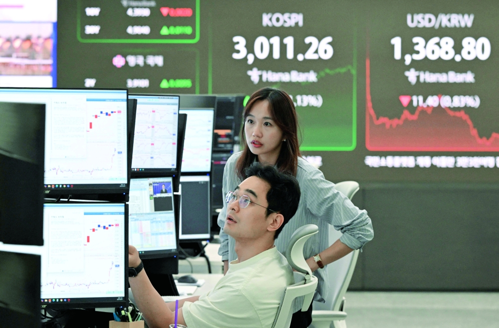Currency dealers monitor exchange rates in front of a big screen showing South Korea's benchmark stock index and the Korean won/$ exchange rate in a foreign exchange dealing room at the Hana Bank headquarters in Seoul. — AFP