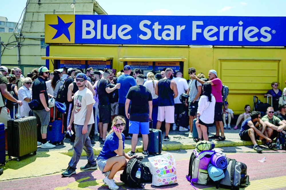 People stand outside ticket offices at the port of Piraeus, near Athens. — AFP