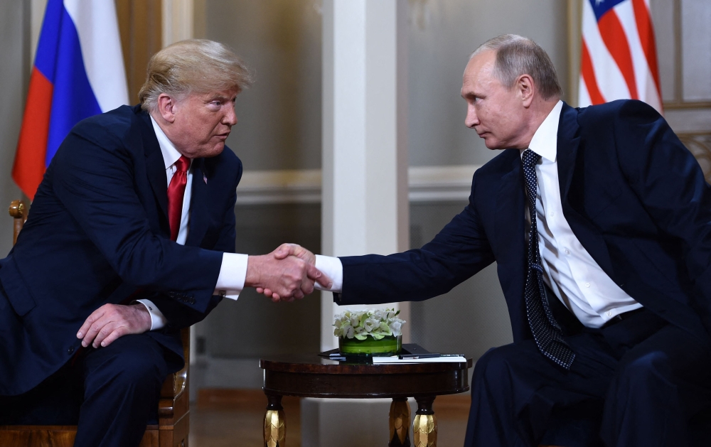 (FILES) Russian President Vladimir Putin (R) and US President Donald Trump shake hands before a meeting in Helsinki on July 16, 2018. 