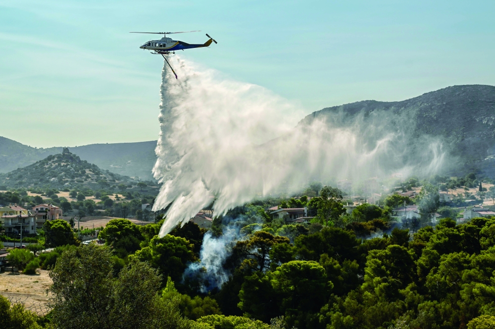 A firefighting helicopter sprays water over a burnt area in Palaia Fokaia. — AFP