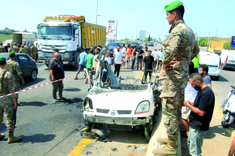 Lebanese army soldiers and onlookers stand near the wreckage of a vehicle. — AFP