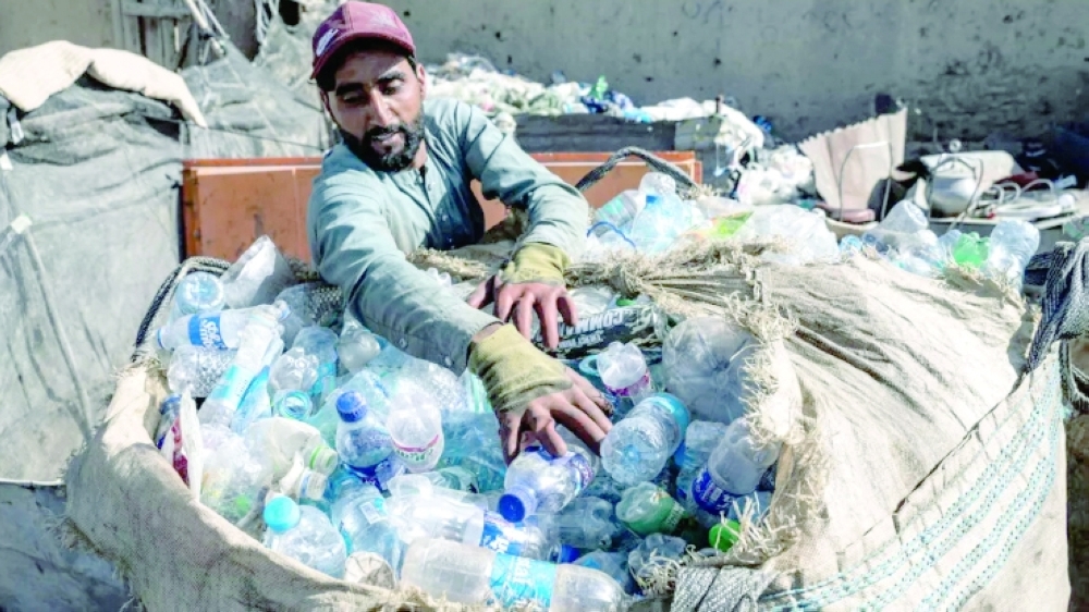 An Afghan worker loads plastic bottles into a sack at a recycling yard in Kabul. — AFP