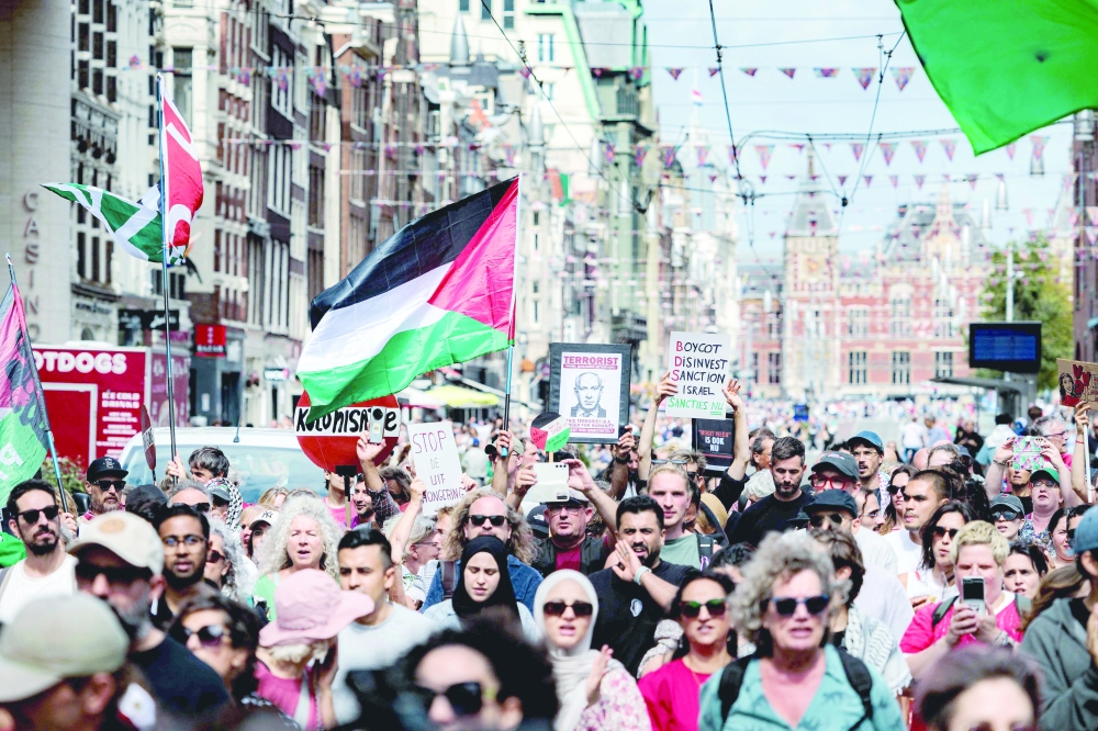 Protesters wave flags as they march during a rally against the war in Gaza, in Amsterdam. — AFP