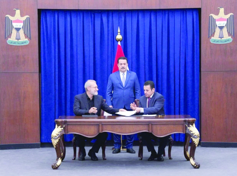 Iraqi PM Mohammed Shia al Sudani looks on as Iraq's National Security Adviser Qasim al Araji and Ali Larijani, secretary of Iran's Supreme National Security Council, sign documents in Baghdad. — Reuters