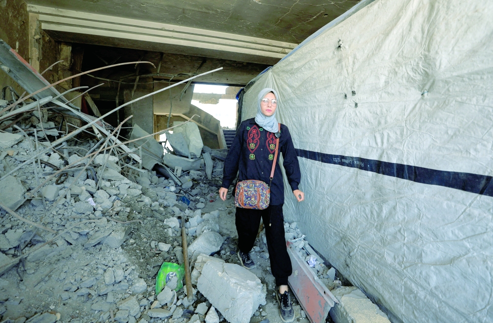 A Palestinian woman walks inside the damaged Islamic University of Gaza, where she shelters, in Gaza City. - Reuters