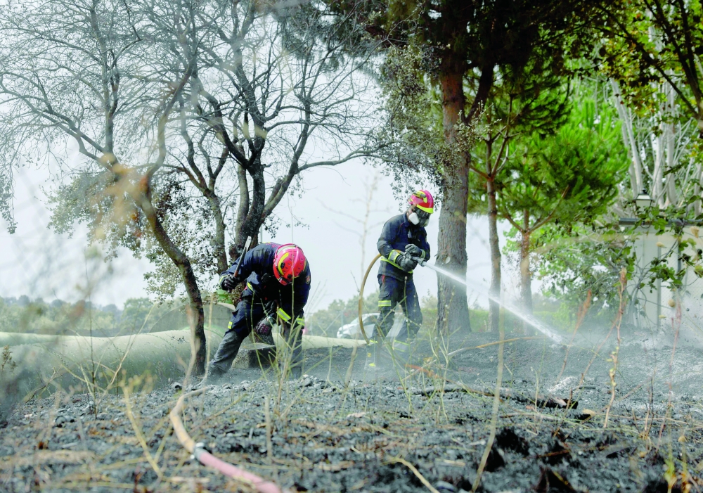 Firefighters cool off the ground close to a school, on the outskirts of Tres Cantos. — AFP