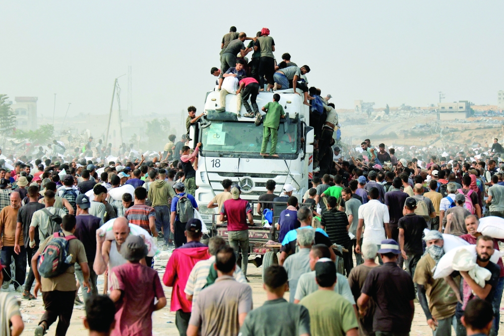 Palestinians scramble to collect aid supplies from trucks, in Khan Yunis. — Reuters