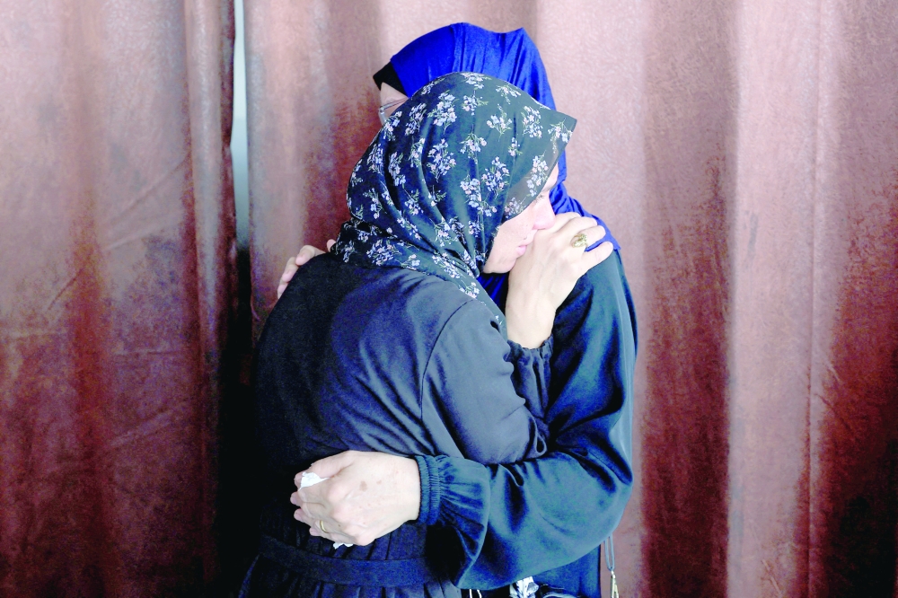 Mourners embrace one another as they attend the funeral of Palestinians killed in Israeli strikes at Al Ahli Arab Hospital in Gaza City on Tuesday. — Reuters