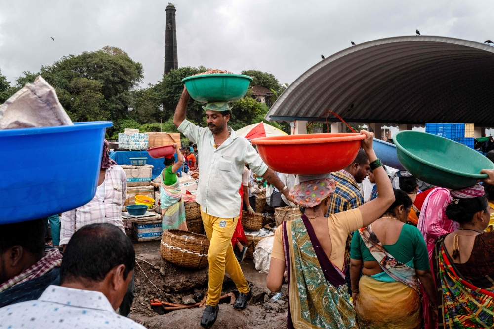 A fisherman carries freshly caught seafood early morning at a crowded market inside the Sassoon Dock in Mumbai
