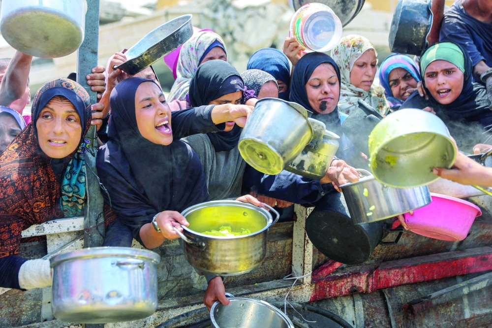 
Palestinians gather to receive cooked meals from a food distribution centre in Gaza City on Wednesday. — AFP 
