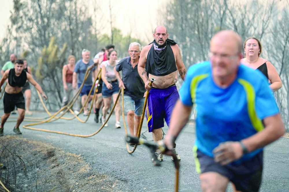 People try to extinguish a wildfire near the village of Larouco, in the province of Ourense, in northwestern Spain. - AFP