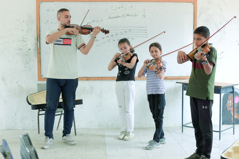 
Palestinian musician Hamada al Kharoubi plays a string musical instrument as he poses for a portrait at Gaza College where instructors from Edward Said National Conservatory of Music train Palestinians, in Gaza City. — Reuters 