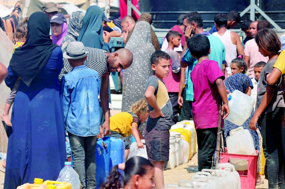 
Displaced Palestinians attempt to fill water tanks in the Mawasi area of Khan Yunis, in Gaza Strip. — AFP 