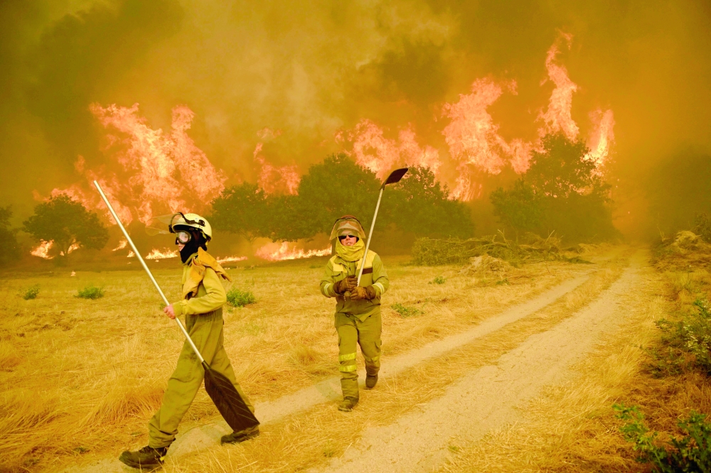 Residents try to battle a wildfire in the village of Santa Baia de Montes, Spain. — AFP