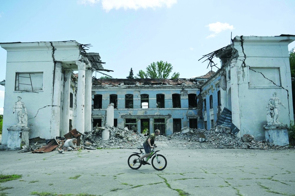 A man rides his bicycle past a destroyed building in Druzhkivka, Donetsk region. — AFP