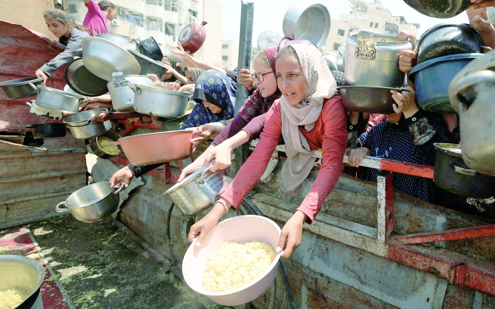 Palestinians wait to receive food from a charity kitchen in Gaza City.