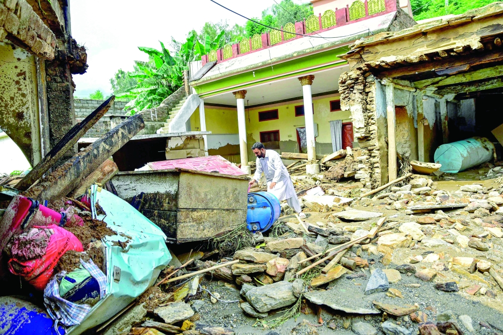 
A man checks his belongings in his damaged house a day after flash floods in the Buner district of the monsoon-hit northern Pakistan on Saturday. — AFP 