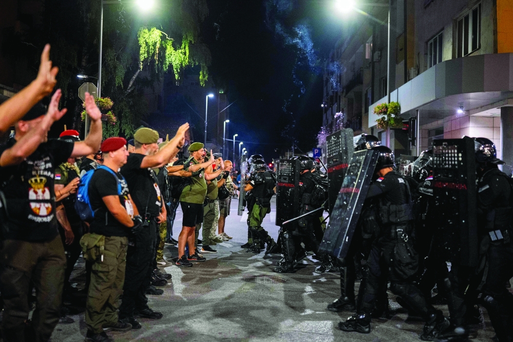 Demonstrators stand in front of riot police officers during a rally, in Valjevo. — AFP