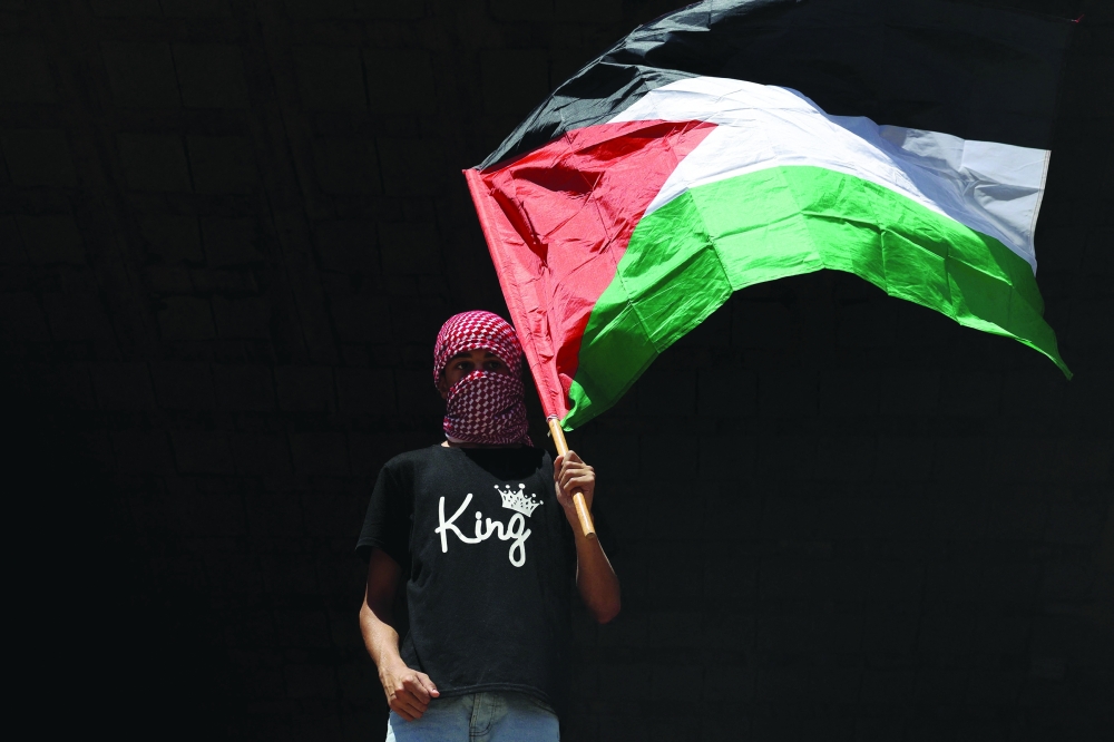 A man carries a flag of Palestine during the funeral of Hamdan Abu Alia, who was killed a day earlier in a reported Israeli raid in Al Mughayyir village, in Ramallah. — AFP
