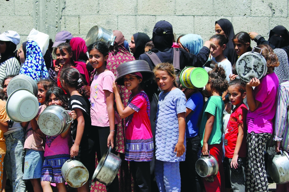 Palestinians gather to receive cooked meals from a food distribution centre in the Nuseirat refugee camp in the central Gaza Strip on Monday. — AFP
