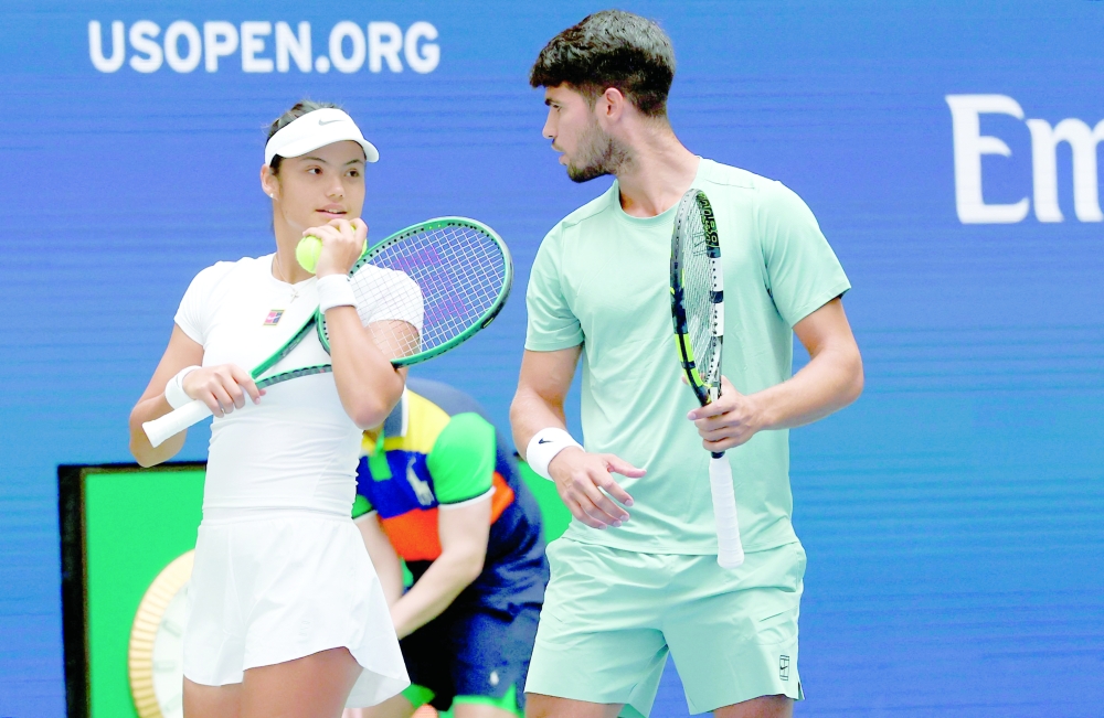 Britain's Emma Raducanu and Carlos Alcaraz of Spain confer during their first round mixed doubles match against Jessica Pegula of the US and Jack Draper of Britain at the US Open tennis tournament at the USTA Billie Jean King National Tennis Center in New York City on August 19, 2025. (Photo by TIMOTHY A. CLARY / AFP)