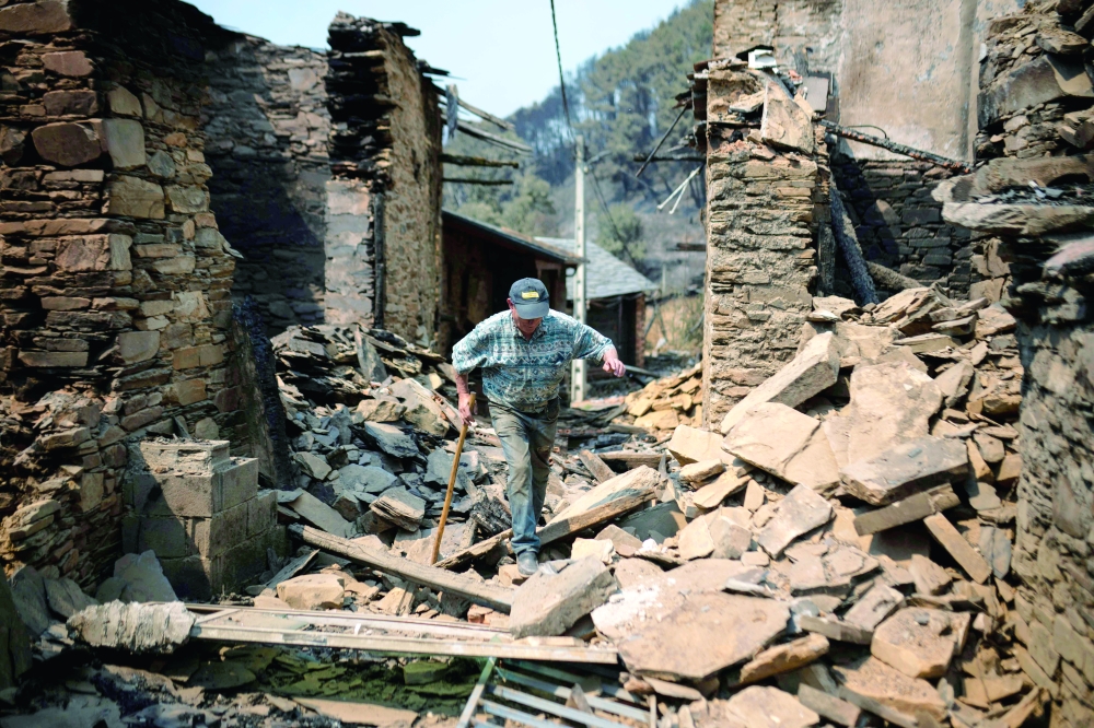 A resident walks among the rubble of houses destroyed by a wildfire, in Ourense. — AFP