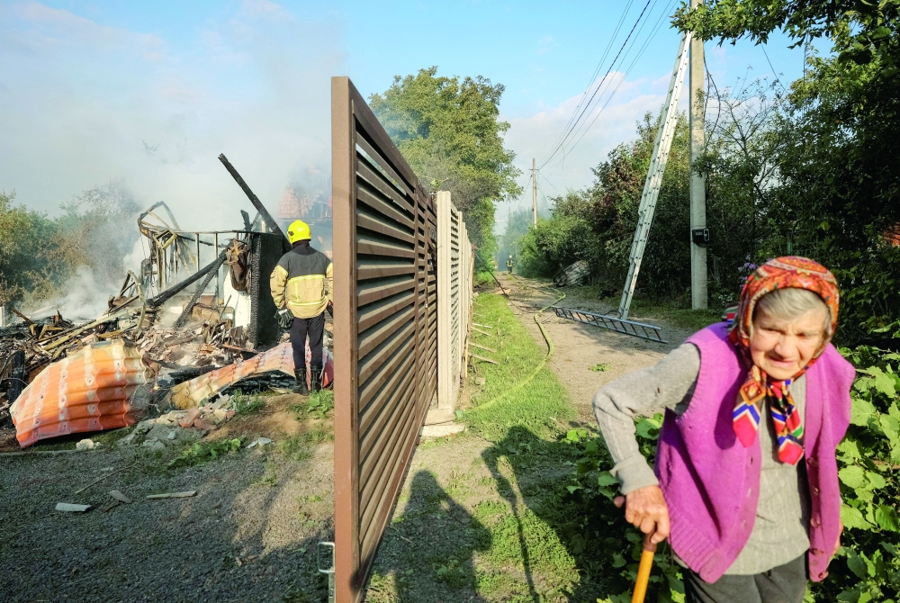 A resident walks along a street as a firefighter works at the site of a Russian missile strike, amid Russia's attack on Ukraine, in the village of Sknyliv on the outskirts of Lviv, Ukraine. - Reuters