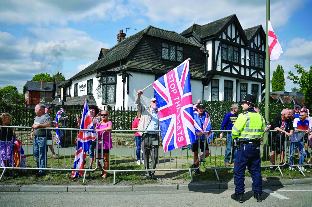 A protestor holds a flag during an anti-immigration protest, south of London. — AFP