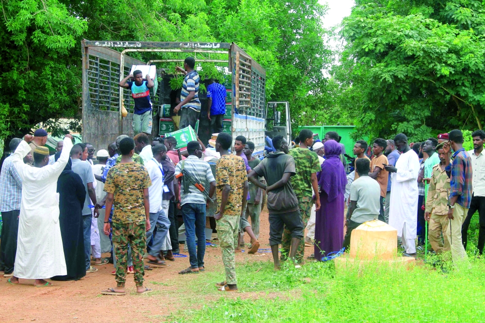 Sudanese, who have recently returned from being displaced, queue to receive humanitarian aid. — AFP