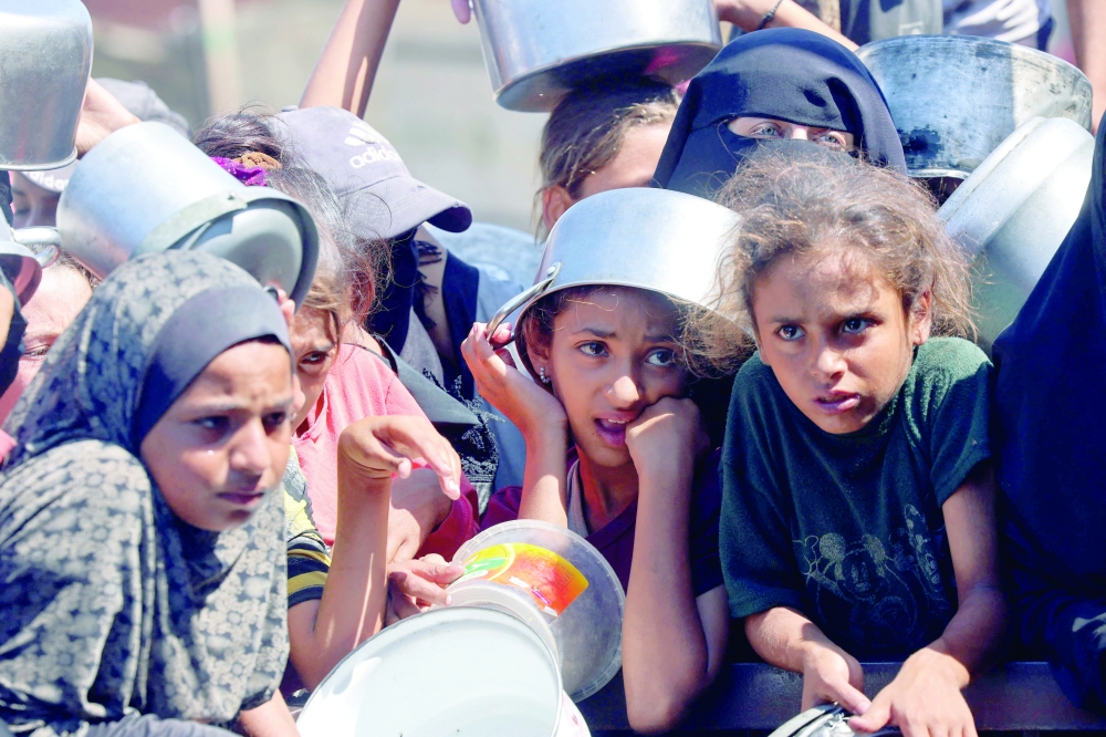 
Palestinians wait to receive food from a charity kitchen in Khan Yunis in the southern Gaza Strip
on Wednesday. — AFP 