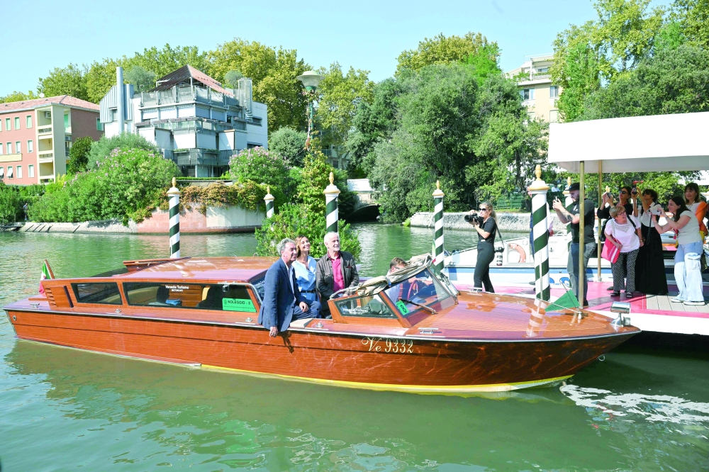 Italian actor Toni Servillo (R), Italian actress Anna Ferzetti and Italian director Paolo Sorrentino arrive at the Excelsior pier on the eve of the 82nd Venice International Film Festival at Venice Lido, on August 26, 2025.   (Photo by Stefano RELLANDINI / AFP)
