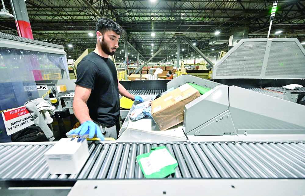 A US postal worker sorting packages during a media tour hosted by the US Postal Service at the Los Angeles Processing and Distribution Centre, the largest in the country. — AFP