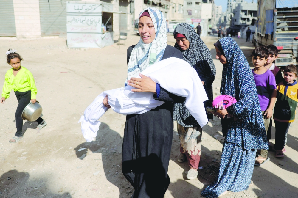 A woman carries the body of a child outside Al Shifa hospital in Gaza City where casualties of Israeli fire were transported ahead of their funerals, on Friday. — AFP