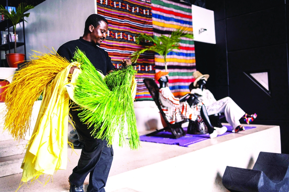 An employee carries clothes as he walks inside Alara concept store in Lagos, on August 20, 2025. With its modern red and black architecture, Al疵a, West Africa's first luxury fashion and decor concept store, stands out in the Nigerian megacity of Lagos. Ten years in business, the store has established itself as a temple of Afro-luxury under the vision of its founder, businesswoman Reni Folawiyo. (Photo by OLYMPIA DE MAISMONT / AFP)
