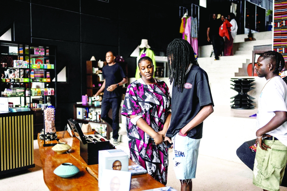 Customers look at items displayed on a table inside Alara concept store in Lagos, on August 20, 2025. With its modern red and black architecture, Al疵a, West Africa's first luxury fashion and decor concept store, stands out in the Nigerian megacity of Lagos. Ten years in business, the store has established itself as a temple of Afro-luxury under the vision of its founder, businesswoman Reni Folawiyo. (Photo by OLYMPIA DE MAISMONT / AFP)
