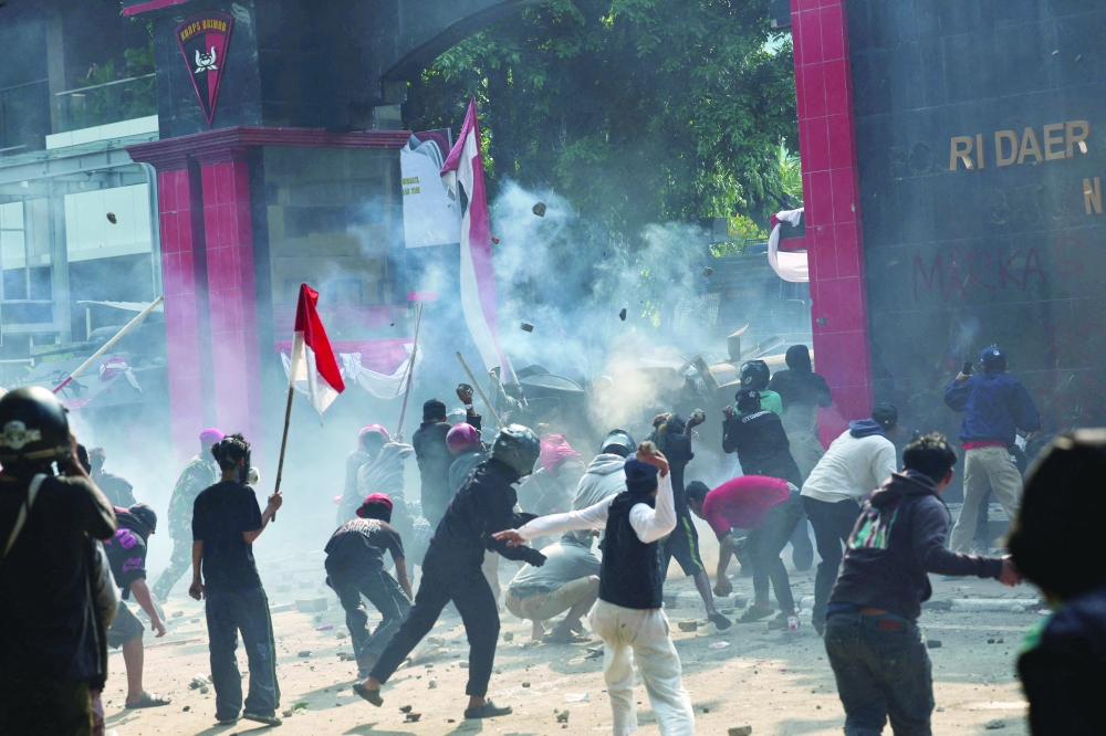 Demonstrators throw stones toward riot police, in Jakarta. — Reuters